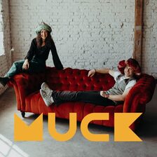 Zwei Schauspieler auf einer Couch und das MUCK Logo